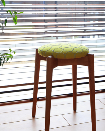 ミナペルホネンのタンバリン生地（イエロー）を張った、丸い座面のスツール。日進木工のトイスツール。